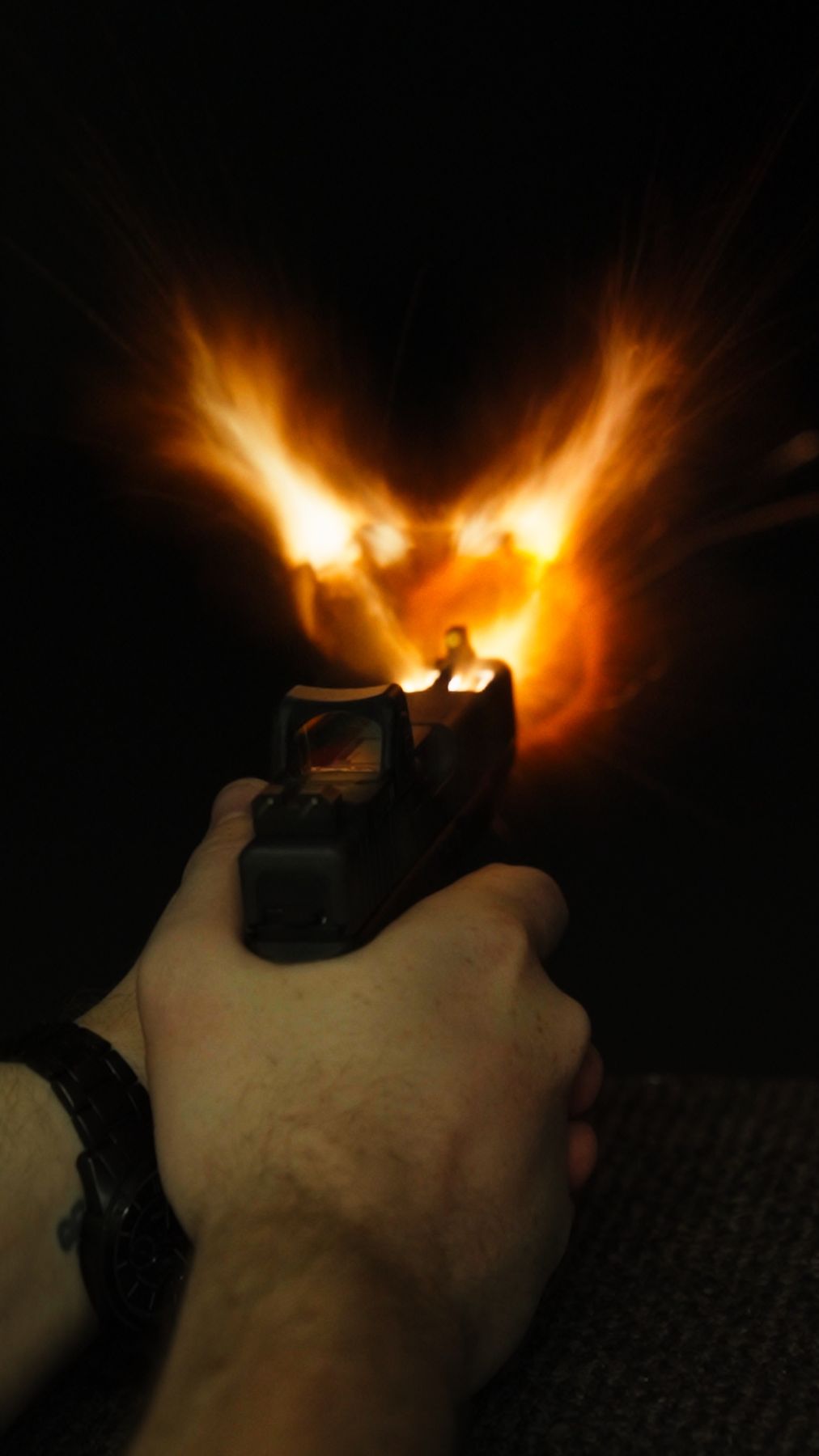 Muzzle flash from a pistol with a red-dot sight, shot in the dark